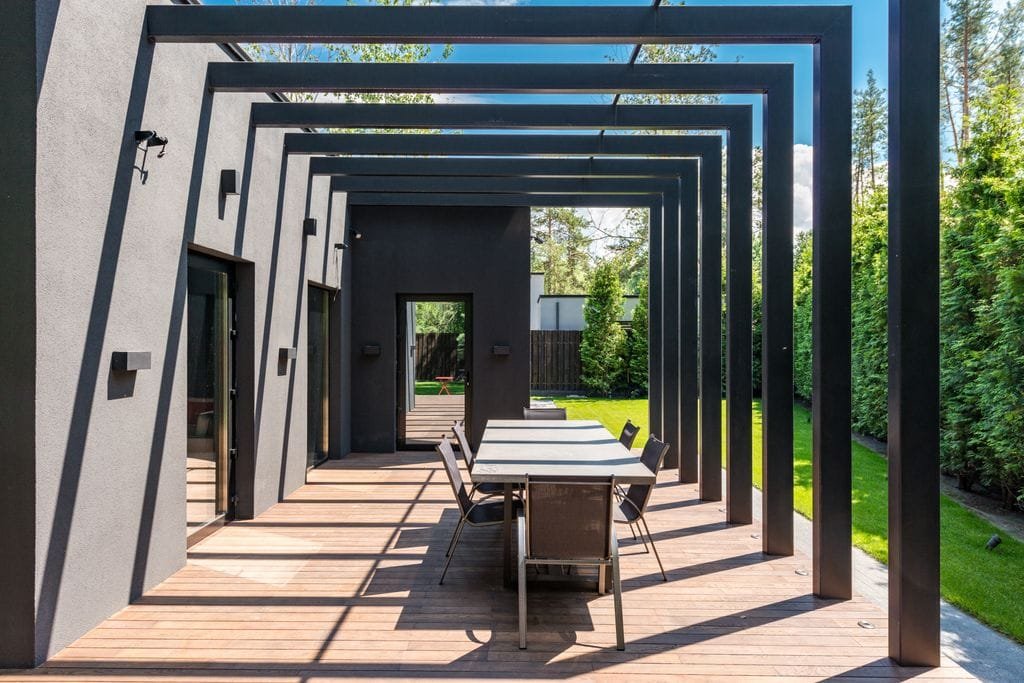 Terrasse contemporaine avec une élégante pergola et un ensemble de repas en plein air.