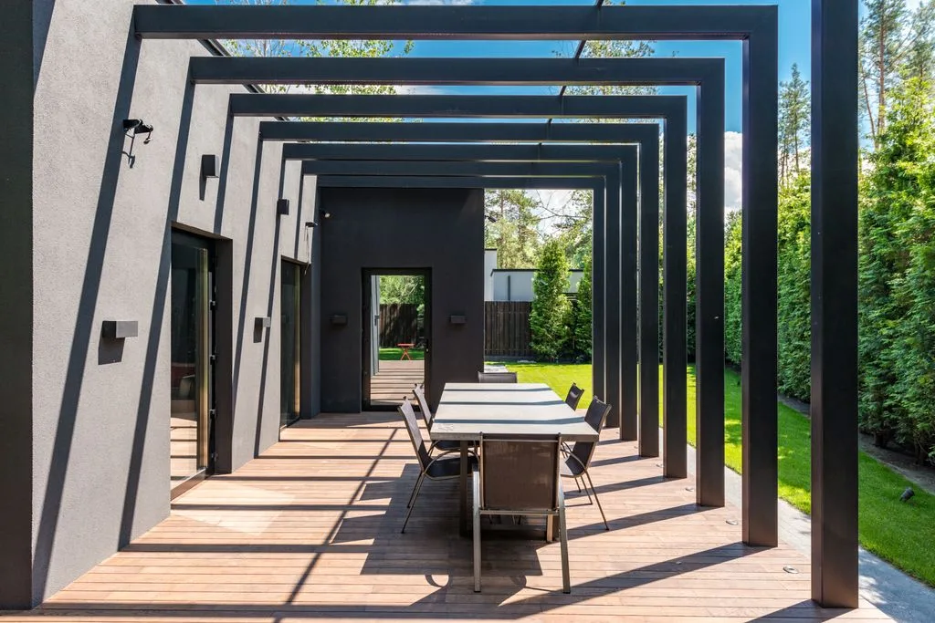 Terrasse contemporaine avec une élégante pergola et un ensemble de repas en plein air.